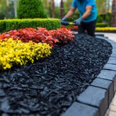 Gardener mulching garden bed outdoors